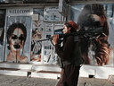 A Taliban fighter walks past a beauty salon with images of women defaced using spray paint in Kabul on August 18, 2021.