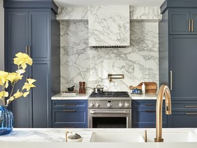 Moody blue cabinetry in Hale Navy by Benjamin Moore and sprays of greenery accent a white kitchen by Two Birds Design in Toronto’s Riverdale neighbourhood.