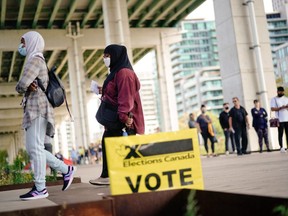 People line up outside a polling station to vote in the federal election, in Toronto, September 20, 2021.