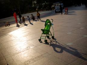 A baby stroller is seen as mothers play with their children at a public area in downtown Shanghai in 2013.