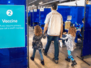 A man arrives with two young girls for his shot at a COVID-19 vaccination clinic in Toronto. Children under 12 are not yet being vaccinated and there is some debate among medical experts about the benefits of doing so.