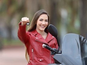 Happy motorcycle buyer showing keys at camera outdoor