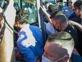 Rocks strike Prime Minister Justin Trudeau in the back as he boards his bus at the end of a campaign stop at the London Co-Operative Brewing Company in London, Ont. on Monday September 6, 2021. (Derek Ruttan/The London Free Press)