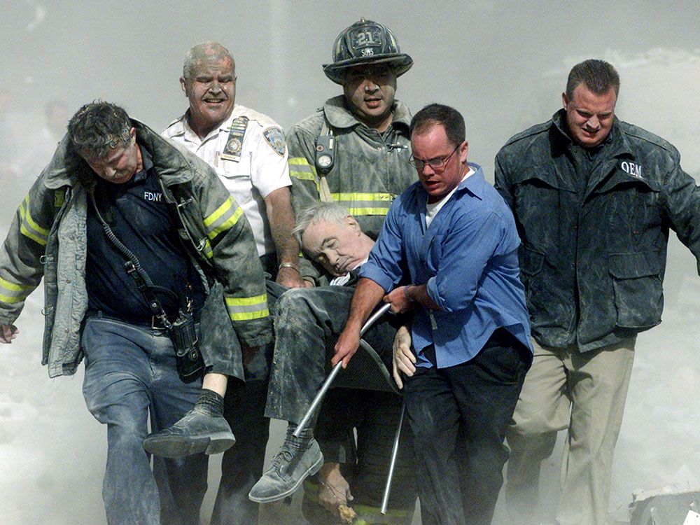  Rescue workers carry mortally injured New York City Fire Department chaplain, the Rev. Mychal Judge, from the wreckage of the World Trade Center in New York City on Sept. 11, 2001. His was the first recorded death on 9/11.