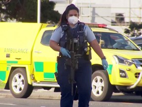 A screen grab shows a police officer walking with a gun outside a shopping mall following a knife attack in Auckland, New Zealand Aug. 3.