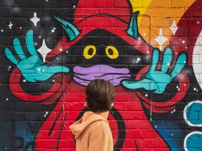 A pedestrian walks past a mural on Toronto's Dundas Street on Sept. 27, 2021. Conflicting medical advice and government directives have left some Canadians distrustful of decrees by government and medical authorities, writes Rex Murphy.