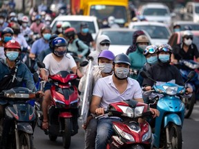 People wearing face masks commute on their motorbikes during the morning peak hour on September 21, 2021 in Hanoi, Vietnam.