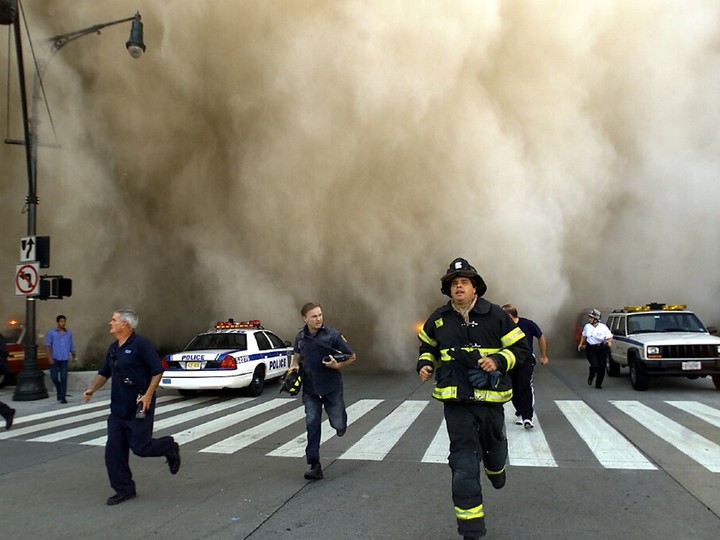  Policemen and firemen run away from the huge dust cloud caused as the World Trade Center’s Tower One collapses after terrorists crashed two hijacked planes into the twin towers, September 11, 2001 in New York City. 