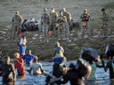 U.S. Border Patrol agents watch as Haitian immigrant families cross the Rio Grande into Del Rio, Texas on September 23, 2021, from Ciudad Acuna, Mexico.