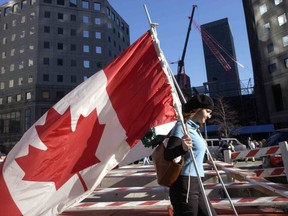 A volunteer from Montreal passes the site of the destroyed World Trade Center with flags from a Canadian ceremony held nearby, in New York City on Dec. 1, 2001.