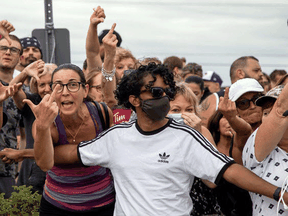 A Liberal volunteer holds back protestors while awaiting a campaign visit by Justin Trudeau, which was cancelled for security concerns, in Bolton, Ont., August 27, 2021.