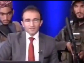 The video shows two armed militants standing behind the host as he delivers his on-air broadcast.