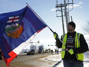 Oilfield worker Kevin Tompkins hoists the Alberta and Canadian flags at a 2018 protest.