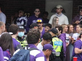 Police officers keep watch on a house party on Broughdale Avenue, near Western University, during Homecoming weekend.