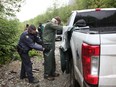 A man is detained and searched after crossing a police checkpoint line, near a camp of protesters obstructing the road to old growth timber logging in the Fairy Creek area of Vancouver Island, on May 24.