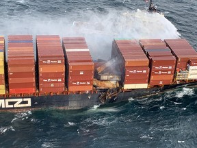 Tugboats pour water on the container ship Zim Kingston after it caught fire off the coast of Vancouver Island.
