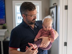 Graham Dickson with his daughter Helen, who is 
11-months-old and not receiving the medical treatment she needs due to a reduction of services from the pandemic, stand for a photograph in their home in Saskatoon on Oct. 8.