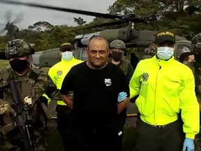 A video grab released on Oct. 23, 2021, by the Colombian Army shows army and police personnel escorting Colombia's most-wanted drug lord and head of the Gulf Clan, Dairo Antonio Usuga a.k.a. "Otoniel,' after his capture, in Bogota.