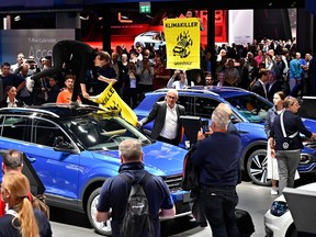 Greenpeace activists holding posters reading "Climate Killers" are pulled from the Volkswagen (VW) cars they stand on as they demonstrate at the booth of Volkswagen, where German Chancellor Angela Merkel touring the fair grounds was expected after officially opening the International Auto Show (IAA) in Frankfurt am Main, western Germany, on September 12, 2019.