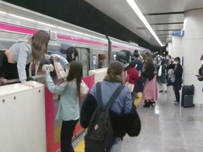 People escape through windows of a Tokyo train line following a knife, arson and acid attack, in Tokyo, Japan on Oct. 31, 2021.