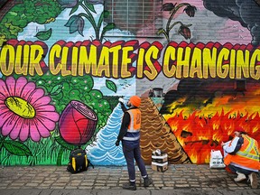 Artists paint a mural near the Scottish Events Centre in Glasgow, which will host the COP26 UN Climate Summit starting Oct. 31. The 30,000 delegates expected to attend will be exempt from the Scottish government's vaccine passport system.