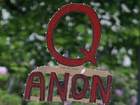 In this May 14, 2020, file photo, a person carries a sign supporting QAnon during a protest rally in Olympia, Wash, USA.