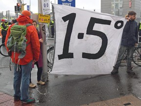A protester holds a banner displaying a "1.5 degree" slogan during a climate change demonstration outside of the COP26 Climate Change Conference in Glasgow on November 12, 2021.