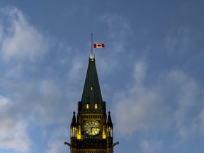 The Canadian flag flies at half mast atop the Peace Tower on Parliament Hill at sunset. Monday, Nov. 1, 2021.