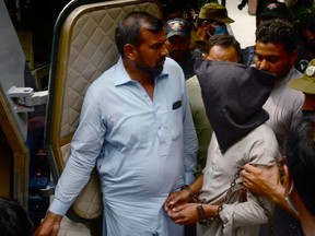 Policemen escort Shafqat Ali (face covered), one of two suspects in a gang-rape case, as they leave from a local court in Lahore on Sept. 15, 2020. Prime Minister Imran Khan said Sept 2020 that the worst sex crimes should be punishable by chemical castration.