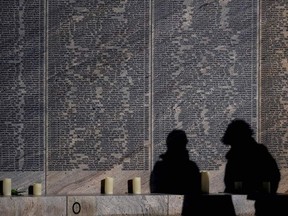 Visitors cast their shadows as they stand in front of the Shoah Name Wall Memorial in Vienna, after it opened to the public on November 10, 2021. - The names of 64,440 Austrian Jews murdered during the Nazi era are inscribed on 160 stone elements.