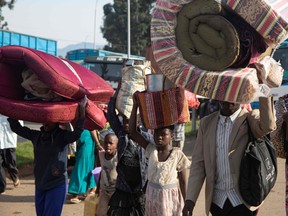 A group of Democratic Republic of Congo (DRC) asylum-seeker carry their belongings at the Bunagana border point in Uganda, on Nov. 10, following a deadly fight between M23 rebels and DRC troops.