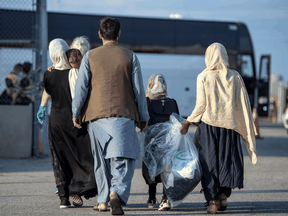 Afghan refugees who supported Canada’s mission in Afghanistan prepare to board buses after arriving in Canada, at Toronto Pearson International Airport August 24, 2021.