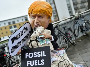 A person wearing a mask depicting Britain's Prime Minister Boris Johnson protests during the UN Climate Change Conference (COP26) in Glasgow, Scotland, November 12, 2021.
