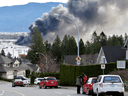 People watch as a fire burns at a RV storage lot, days after rainstorms lashed British Columbia, triggering landslides and floods, and shutting highways, in Abbotsford, B.C., November 17, 2021.