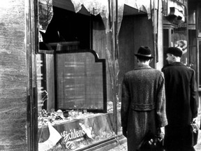 Men view a Berlin store window that was smashed on Kristallnacht.