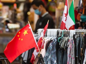 Chinese and Canadian flags are displayed along with clothing outside a Toronto store in a file photo from Oct. 22, 2021. A Conservative Senator says that Canada is “subsidizing” the cultural genocide of the Uyghur people by allowing the import of goods made with slave labour.