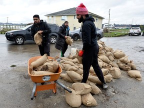 Friends of the Purewal family help sandbag their property amid flooding in Abbotsford, B.C., on Nov. 20, 2021.