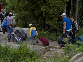 A 2018 photo of a family with their luggage in tow at the illegal border crossing at Roxham Road near Perry Mills, New York. After being closed in March, 2020 due to fears over COVID-19, the crossing is once again being staffed by RCMP.