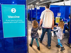 A man arrives with two young girls for his shot at the COVID-19 vaccination clinic at the Ontario Food Terminal in Toronto on May 11.