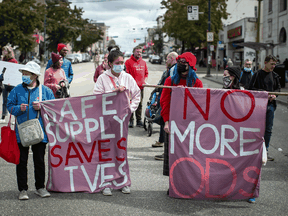 People hold banners at a march in Vancouver on International Overdose Awareness Day to remember those who died during the overdose crisis and to call for a safe supply of illicit drugs.
