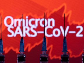 Syringes with needles are seen in front of a displayed stock graph and words "Omicron SARS-CoV-2" in this illustration taken on Nov. 27, 2021.