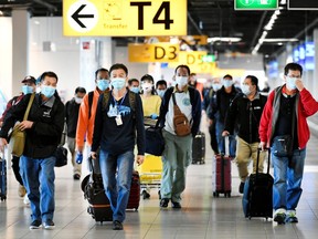 People wearing protective face masks walk, as Schiphol Airport reduces its flights due to the coronavirus disease (COVID-19) outbreak, in Amsterdam, Netherlands April 2, 2020.