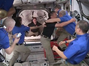 This screen grab taken from the NASA live feed shows crew members of the International Space Station welcoming crew members of the SpaceX's Crew Dragon spacecraft after docking an opening hatches, on April 24.