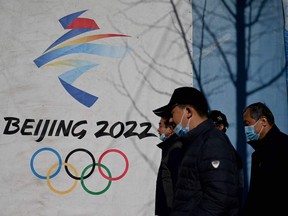 In this file photo taken on December 01, 2021, people walk past the Beijing 2022 Winter Olympics logo at the Shougang Park in Beijing. - Canada will not send officials to the Beijing Olympics in February, Trudeau announced on December 8, 2021, joining the US and other allies' diplomatic boycott of the Games.