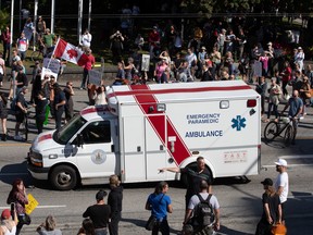 An ambulance passes through a crowd of people at an anti-vaxxer rally in Vancouver on Sept. 1.