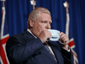 Ontario Premier Doug Ford puts his mask back on after speaking during a press conference at Queen's Park in Toronto, Wednesday, December 15, 2021.