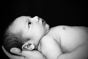 A close up portrait of a newborn baby in his mother's arms. Copy space in black background. Captured with a Canon 5D Mark II.