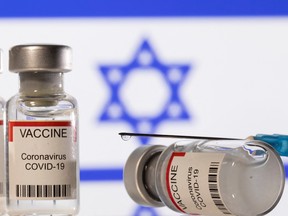 Vials labelled "VACCINE Coronavirus COVID-19" and a syringe are seen in front of a displayed flag of Israel in this illustration taken December 11, 2021. REUTERS/Dado Ruvic/Illustration