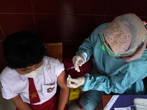 A student receives a dose of the Sinovac Biotech Ltd. Covid-19 vaccine at the SD Cinere III elementary school in Jakarta, Indonesia, on Tuesday, Dec 21, 2021.