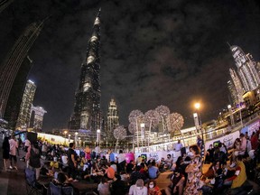 Dieses mit einem Fischaugenobjektiv aufgenommene Bild zeigt Menschen, die am 31. Dezember 2021 unter dem Burj Khalifa in Dubai auf das Silvesterfeuerwerk warten.